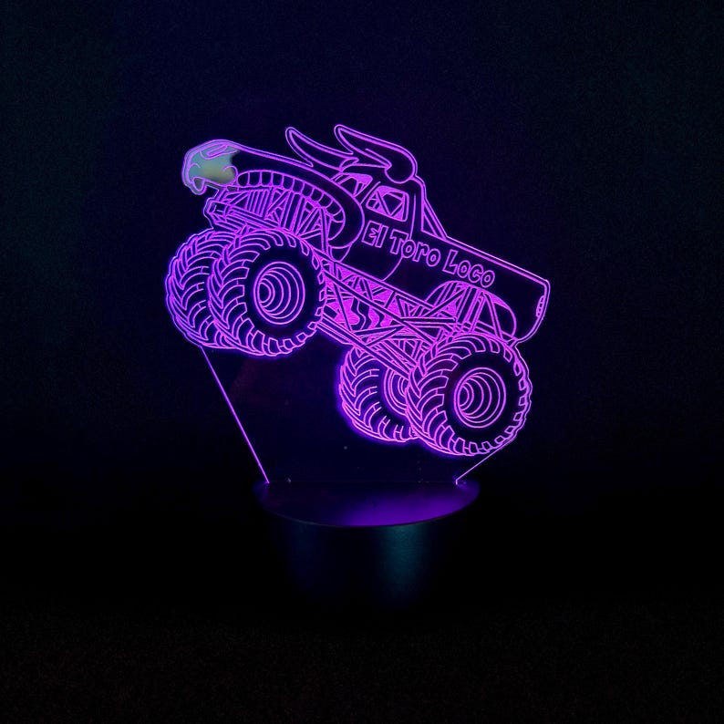 May include: A purple LED night light featuring a monster truck design. The truck has large tires, a bull head, and the text "El Toro Loco". The light is on a black base and emits a purple glow.