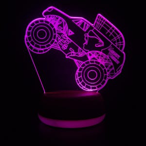 May include: A purple 3D printed night light shaped like a monster truck with the words "Monster Masher" on the side. The truck is on a black base with a white ring around the bottom.