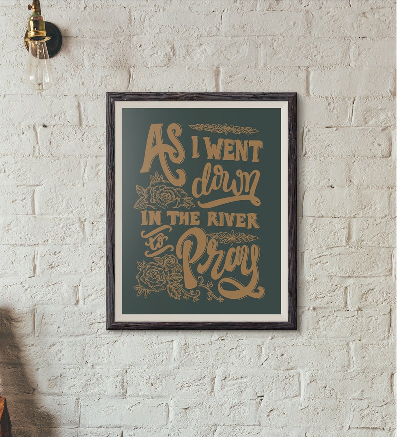 May include: A framed print with a dark green background and gold lettering. The text reads "As I went down in the river to pray".