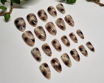 Op de afbeelding: Set van 20 bruine en zwarte gevlekte kunstnagels met een puntige ovale vorm.