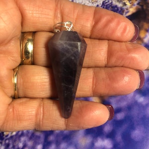 Könnte beinhalten: Ein violetter Amethyst-Kristall-Pendel mit einer silbernen Kette.