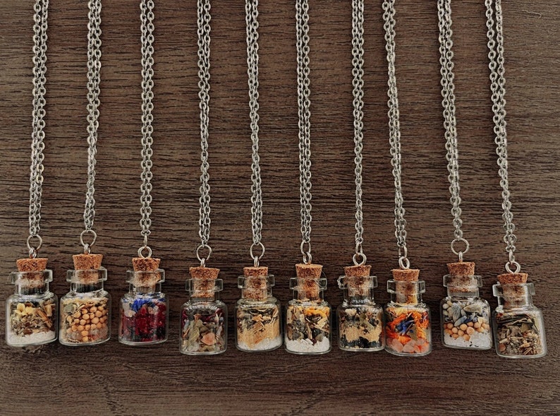 May include: Ten silver chain necklaces with small glass bottles filled with dried herbs and flowers. The bottles have cork stoppers.