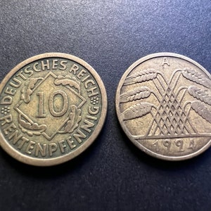 May include: Two German coins, one with the inscription "Deutsches Reich 10 Pfennig" and the other with a depiction of wheat stalks and the year "1994".