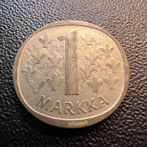 May include: A silver Finnish 1 Markka coin with a snowflake design and the word "Markka" inscribed around the edge.