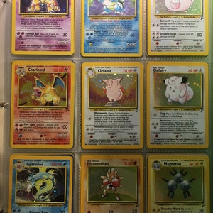 May include: A collection of Pokemon trading cards featuring various characters, including Alakazam, Blastoise, Chansey, Charizard, Clefable, Clefairy, Gyarados, Hitmonchan, Magneton. The cards are arranged in a binder with a yellow background.