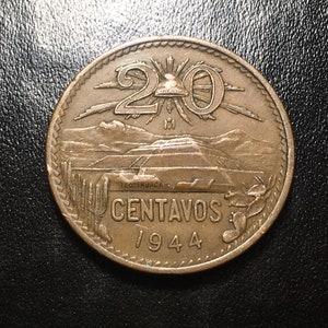 May include: A copper-colored Mexican coin with the number "20" and the word "CENTAVOS" inscribed on it. The coin also features a depiction of the Pyramid of the Sun in Teotihuacan, Mexico, and the year "1944".