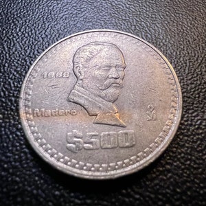 May include: A silver Mexican coin with a portrait of Francisco I. Madero, the text "1989 Madero" and the denomination "$500".