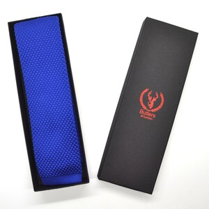 May include: A blue knitted tie in a black box with the text "Butlers of London" and a stag logo.