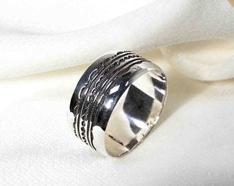 May include: A silver ring with a wide band and intricate etched designs. The band is rounded and has a smooth, polished finish.