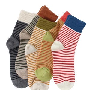 May include: A collection of colorful socks with striped patterns. The socks feature various color combinations, including gray, tan, olive green, orange, red, and blue. Each sock has a different color scheme, with stripes running horizontally across the fabric.