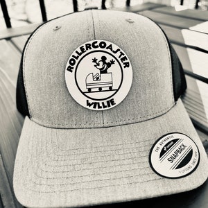 May include: Gray and black baseball cap with a black and white patch that says "Rollercoaster Willie" and features a cartoon mouse riding a roller coaster. The cap has a black mesh back and a white "The Authentic Snapback" label.