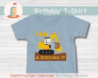 May include: A light blue t-shirt with a yellow construction vehicle graphic. The vehicle has a number 3 on the side and the text "I AM 3 & DIGGING IT". Construction Vehicles Birthday Theme.