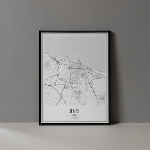 Può includere: Una stampa incorniciata in bianco e nero della mappa di Bari, Italia. La mappa mostra le strade e le infrastrutture della città. Il nome della città e le coordinate sono stampati in basso.