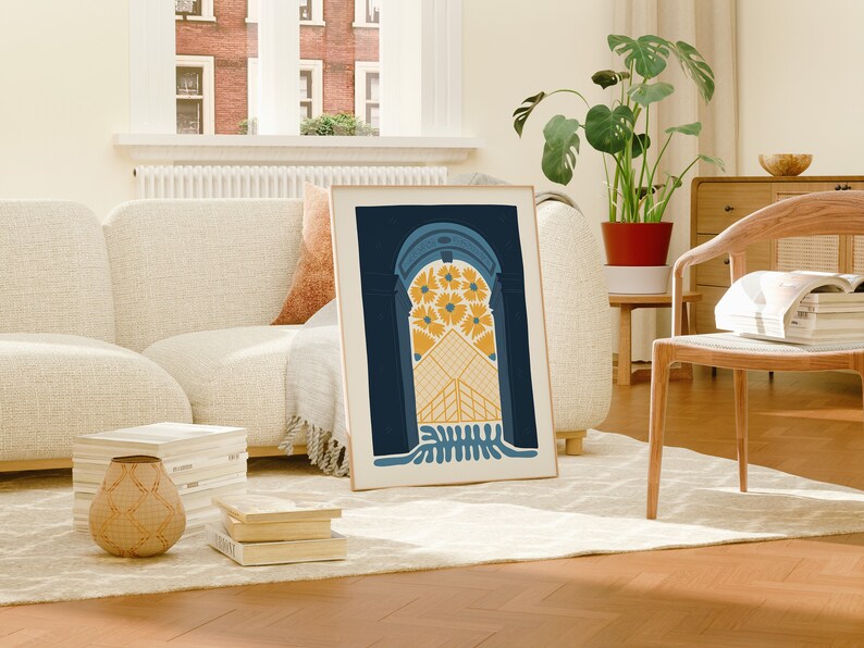 May include: A framed print of an abstract archway design with yellow and blue colors. The archway is filled with yellow flowers and a geometric pattern. The print is hanging on a wall in a living room setting.