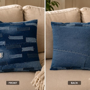 May include: Square denim pillow with a patchwork design on the front. The front of the pillow features various shades of blue denim patches. The back of the pillow is a solid blue denim. The pillow is on a beige sofa.