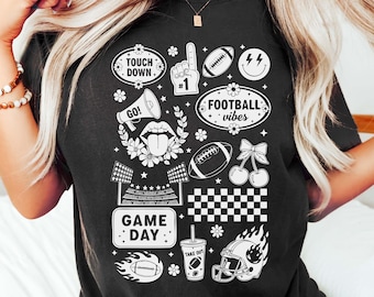 May include: Black t-shirt with white graphic designs related to football. The shirt features text and images of footballs, a helmet, a megaphone, and the words "Touch Down", "Football Vibes", and "Game Day".