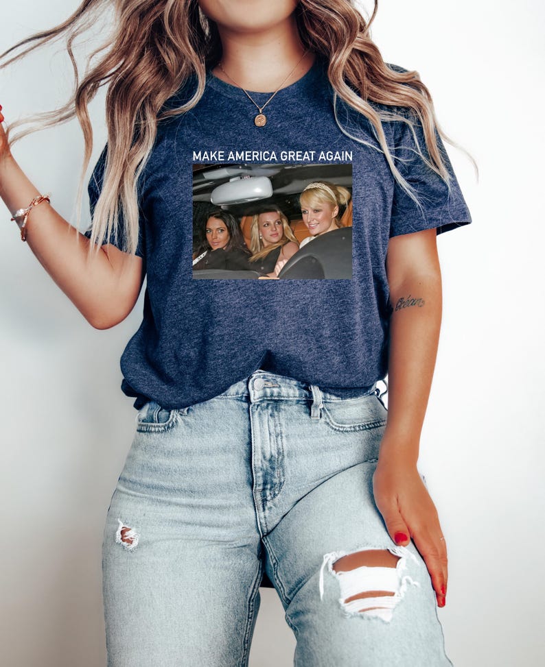 Puede incluir: Una camiseta azul marino con un gr&aacute;fico blanco de tres mujeres en un coche. El texto "MAKE AMERICA GREAT AGAIN" est&aacute; impreso sobre el gr&aacute;fico.