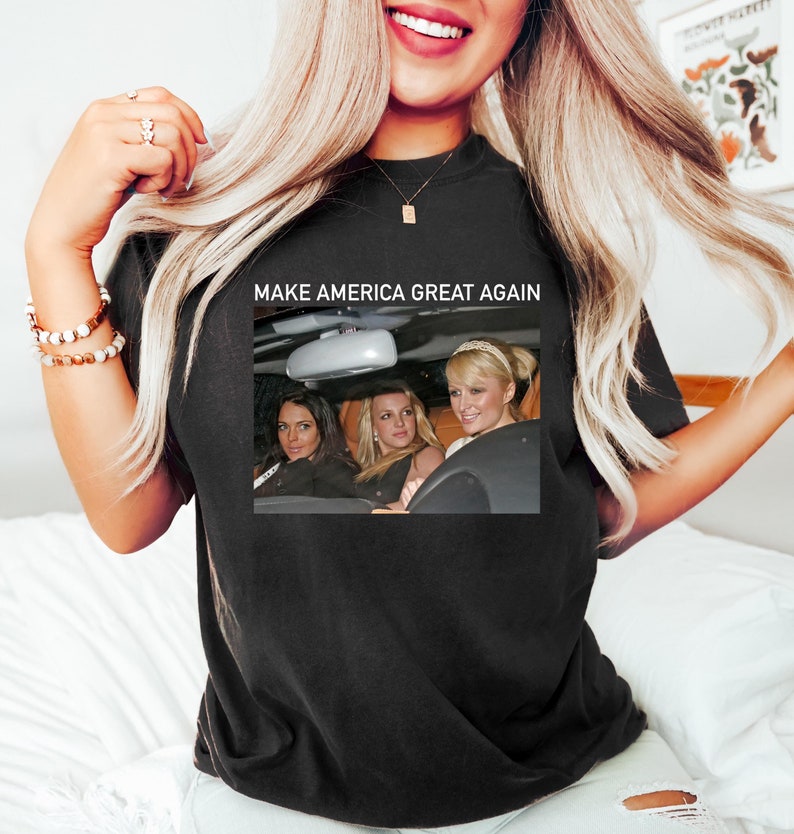 Puede incluir: Camiseta negra con un gr&aacute;fico blanco de tres mujeres en un coche. El texto "Make America Great Again" est&aacute; por encima de la imagen.