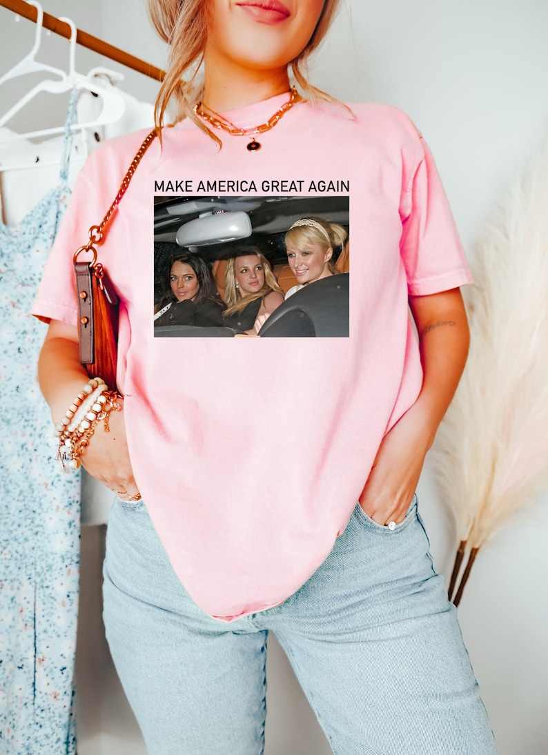 Puede incluir: Camiseta rosa con el texto "MAKE AMERICA GREAT AGAIN" y una foto de tres mujeres en un coche.