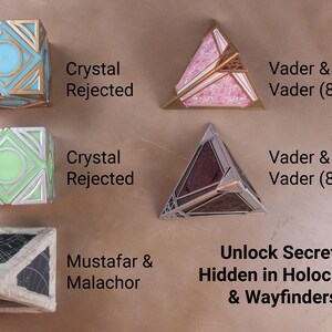 K&ouml;nnte beinhalten: Sammlung geometrischer Holocrons und Wegfinder in verschiedenen Farben. Enth&auml;lt W&uuml;rfel- und Pyramidenformen mit Texten wie "Crystal Rejected", "Vader & Vader (8-Ball)", "Mustafar & Malachor" und "Unlock Secrets Hidden in Holocrons & Wayfinders".