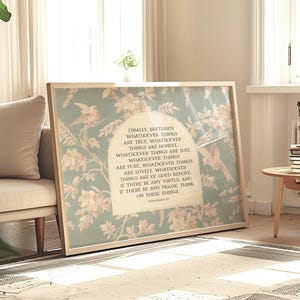 May include: A framed print featuring a floral and bird design in soft green and cream tones. The print includes a passage of text in a classic font. The frame is a light wood color, and the artwork is displayed in a well-lit room.