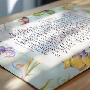 Print of Ralph Waldo Emerson Success poem written in a white center rectangle, surrounded by a background of light blue with vintage floral artwork. Pictured as poster lying on top of a desk.