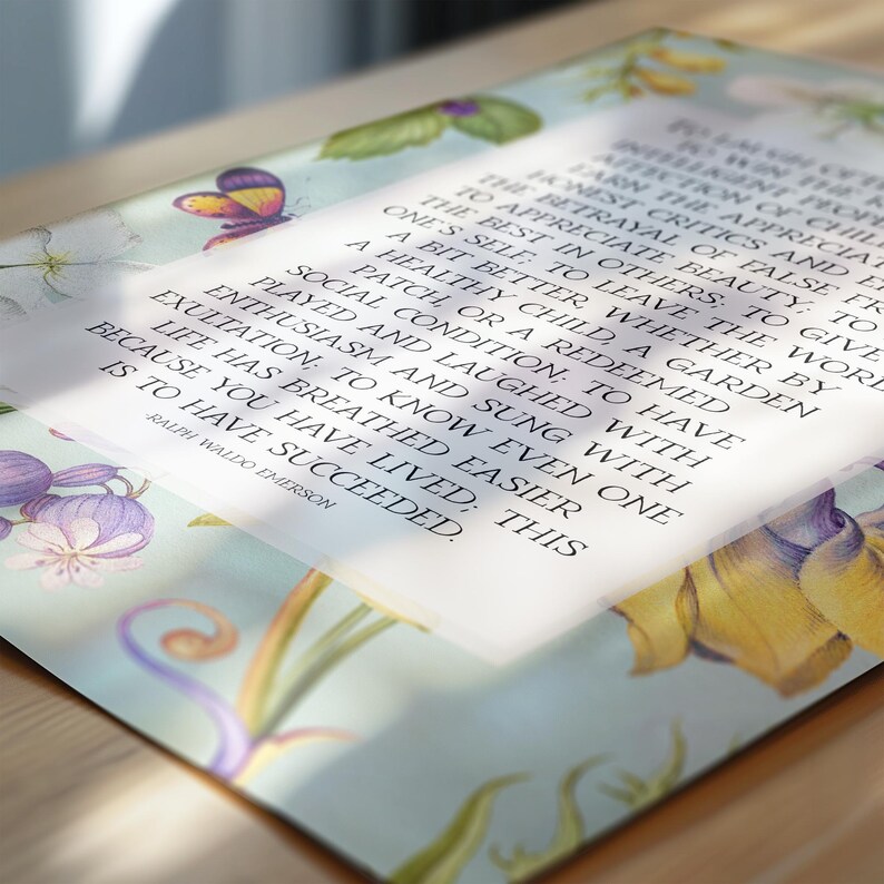 Print of Ralph Waldo Emerson Success poem written in a white center rectangle, surrounded by a background of light blue with vintage floral artwork. Pictured as poster lying on top of a desk.