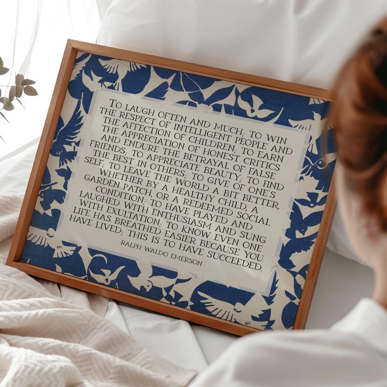 May include: A framed print featuring a quote by Ralph Waldo Emerson. The print has a cream-colored background with a blue floral pattern border. The text is in black, and the frame is a light brown color.