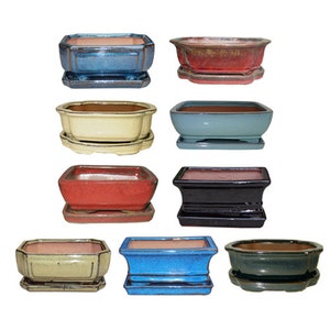 May include: A collection of ceramic bonsai pots in various colors, including blue, red, black, and cream. Each pot has a matching saucer. The pots are rectangular and octagonal, with a glossy finish. These pots are designed for bonsai trees.