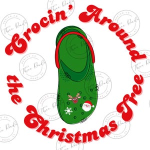 Puede incluir: Chancla verde con correas rojas y decoraciones navideñas, incluyendo un reno, Santa Claus y un copo de nieve. El texto "Crocin' Around the Christmas Tree" está escrito en rojo alrededor de la chancla.