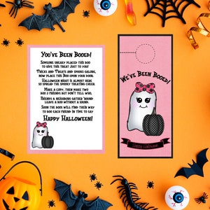 May include: A pink and white ghost with a pink bow and a black pumpkin holds a sign that says "We've Been Booed!"  The sign is attached to a door with a hole cut out for the sign.  The background is orange with black bats and spiders.