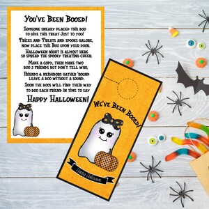 May include: A printable Halloween door hanger featuring a cute ghost with a pumpkin and the text "You've Been Booed!" and "We've Been Booed!"
