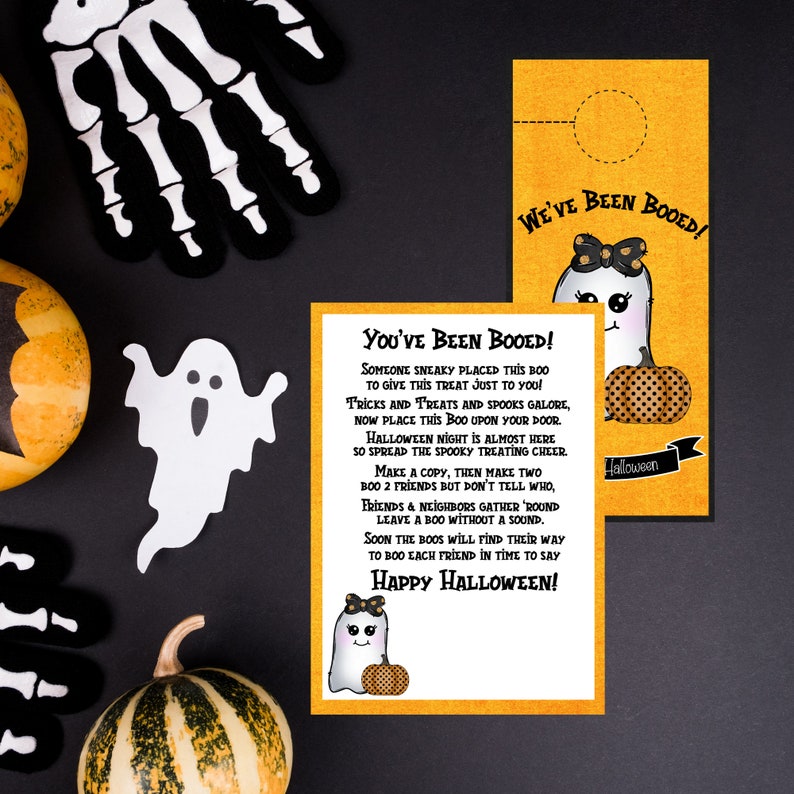 May include: Two printable Halloween door hangers featuring a cute ghost with a pumpkin. The text on the door hangers reads "You've Been Booed!" and "We've Been Booed!"