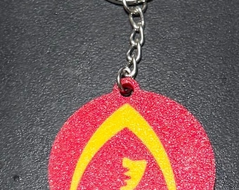 May include: A red and yellow keychain with a stylized logo. The logo is a yellow arch with a smaller yellow shape inside. The keychain is attached to a silver key ring.