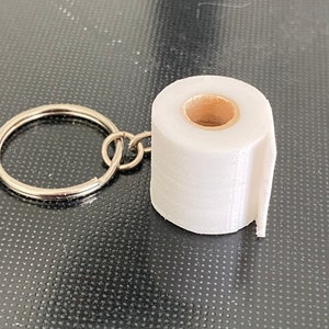 May include: A white 3D printed toilet paper roll keychain with a silver key ring.