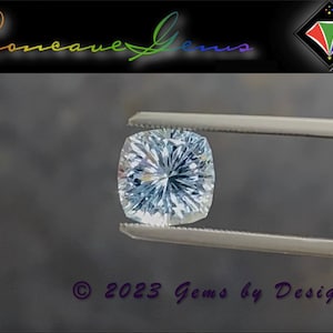 May include: A clear, faceted, cushion-cut gemstone held by tweezers. The gemstone has a light blue hue and is set against a gray background. The text "Concave Gems" is visible in the top left corner of the image.