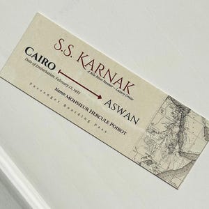K&ouml;nnte beinhalten: Ein Boarding Pass im Vintage-Stil f&uuml;r die S.S. Karnak, ein Nil-Dampfer. Der Pass, mit einer Karte, zeigt die Reise von Kairo nach Assuan, datiert vom 12. Februar 1937, und den Namen des Passagiers, Monsieur Hercule Poirot.