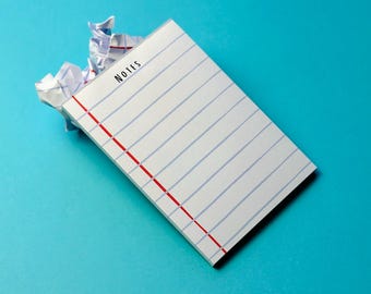 May include: A white notepad with blue horizontal lines and a red vertical line on the left side. The word "NOTES" is printed at the top. Crumpled paper is next to the notepad on a turquoise background.