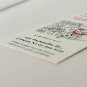 Op de afbeelding: Een witte visitekaartje met zwarte tekst die luidt: "Somewhere here 33a Peckender St. London N1 01-389 9112 Phone today for the whole solution to your problem". Een zwart-witte kaart met een rode cirkel op de achtergrond.