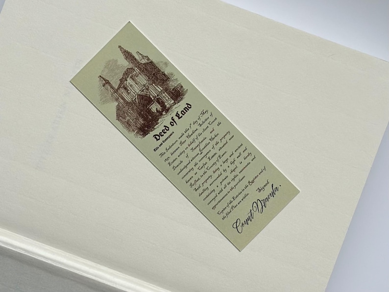 May include: A rectangular bookmark with the text "Deed of Land" and an illustration of a building. The bookmark is light green with brown text and illustration. The background is a light cream color.