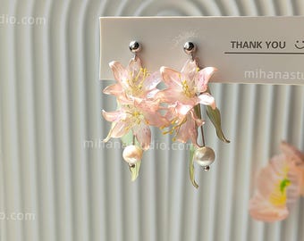 Pendientes de resina con forma de lirio, esculpidos a mano, con perlas de agua dulce y detalles botánicos en plata de ley.