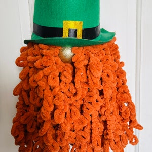 May include: A green leprechaun hat with a black band and gold buckle, with a long, orange, fuzzy beard.