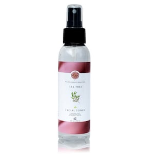 Könnte beinhalten: Eine durchsichtige Glasflasche mit schwarzem Sprühkopf, die Gesichtswasser mit Teebaumöl enthält. Die Flasche hat ein rosa-weißes Etikett mit dem Text "Tea Tree Facial Toner" und einem kleinen Bild eines Teebaumblattes.