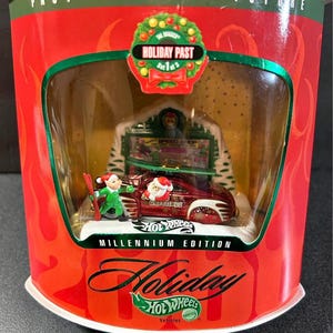 May include: A Hot Wheels Millennium Edition Holiday Past collectible. The red and white car has a Santa Claus figure and the word "Greetings". The packaging is red with the words "Past Present Future" and "Holiday".