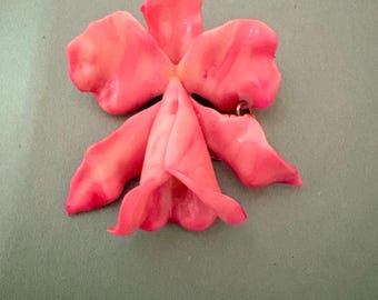 Pink ceramic (or porcelain) flower brooch, most often described as an orchid or lily style pin, with a dangling Miraculous Medal charm.