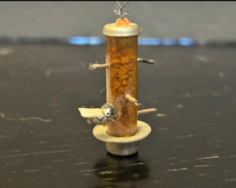 dollhouse miniature bird feeder, specifically a 1:12 scale "thistle" or "tube" style feeder.