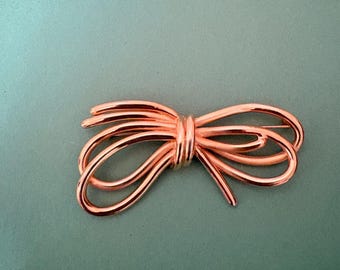 multi-loop wire bow/ribbon brooch in a rose-gold or coppery gold tone.