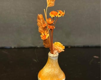 miniature ceramic bud vase featuring a small dried flower arrangement.