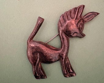 copper- or bronze-toned metal leaping deer (or gazelle/stag) brooch in a stylized, somewhat abstract form