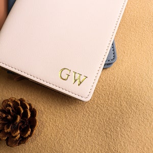 May include: A pink leather journal with gold lettering that reads "GW" on the front cover.